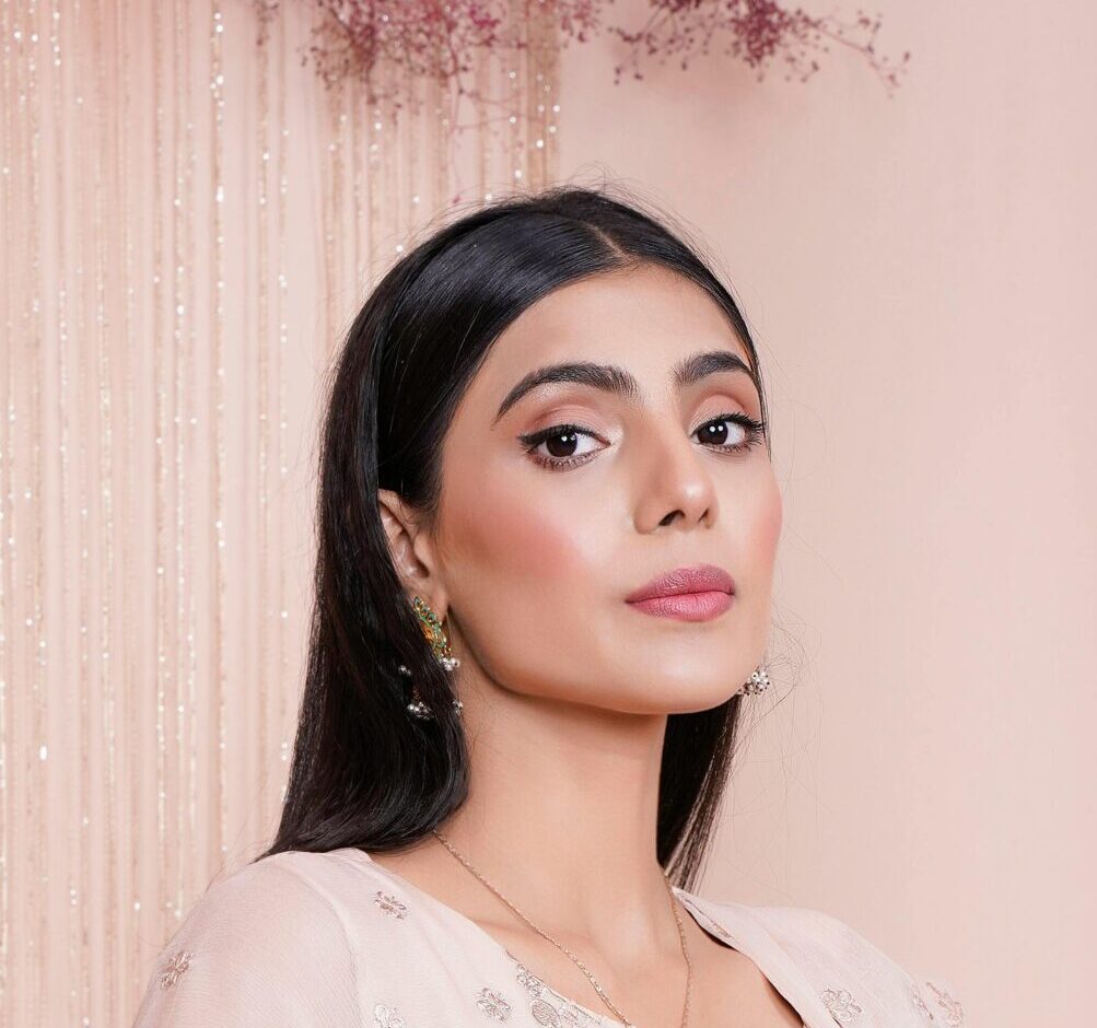 A stylish woman poses in an elegantly embroidered dress, showcasing fashion and beauty.